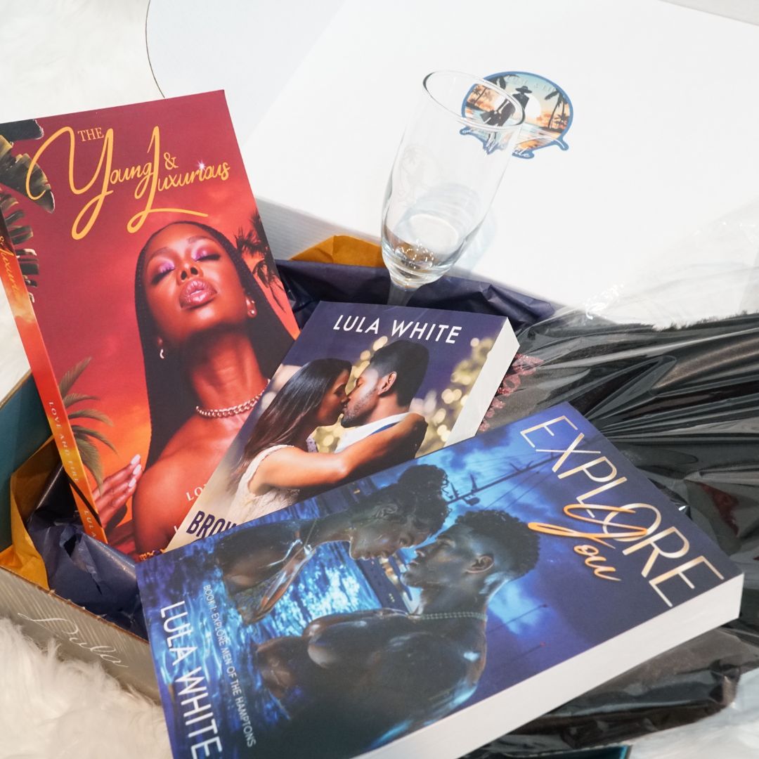 three romance novels and champagne flute inside a book box with furry house slippers